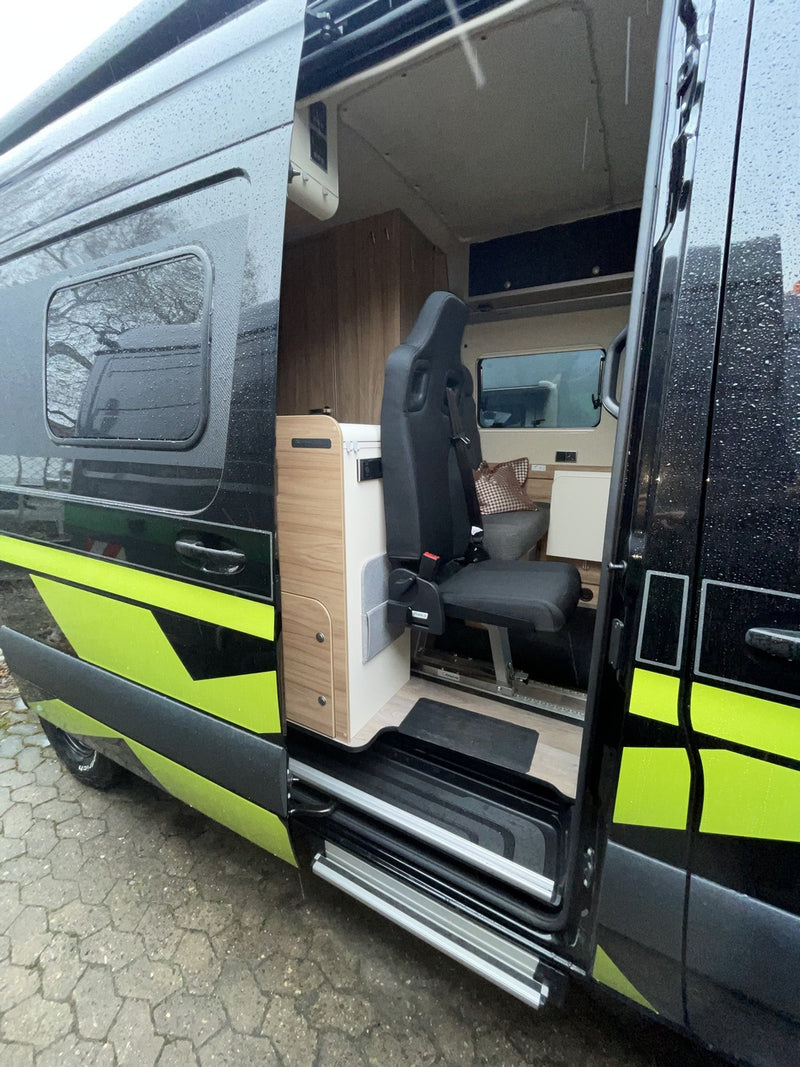 Schwarzer Camper-Van mit nachgerüstetem Einzelsitz an der Schiebetür